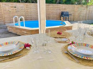 a table with wine glasses and plates and a pool at Villa SELAH in Le Moule