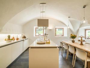 a kitchen with white cabinets and a long table at Chalet Wolfbachgut in Taxenbach