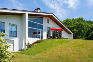 a white house with a red umbrella on a lawn at Espace, Luxe, Calme Et Nature in Saint-Martin-de-Seignanx