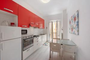 a kitchen with white appliances and red cabinets at Arenzano A Due passi dal mare in Arenzano
