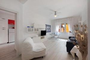 a white living room with a white chair and a kitchen at Arenzano A Due passi dal mare in Arenzano