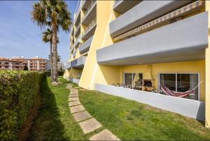a building with a palm tree next to a sidewalk at Casa Cláudia - Cond do Mar in Lagos