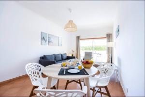 a dining room and living room with a table and chairs at Casa Cláudia - Cond do Mar in Lagos