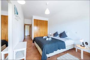 a bedroom with a large bed with a blue blanket at Casa Cláudia - Cond do Mar in Lagos +17 photos