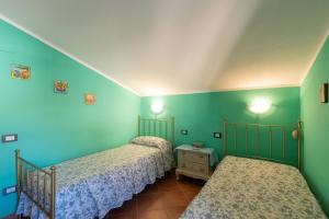 two beds in a room with blue and green walls at Casa Delle Pomelie in Trappeto