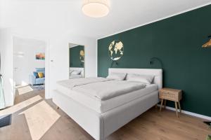 a white bed in a room with a green wall at Fewo Bergfeld in Mosbach