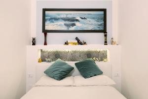a bed with two pillows and a television above it at Smart Home Loano in Loano