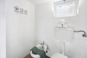 a white bathroom with a toilet and a window at Abrigo do Pescador in Aljezur +16 photos
