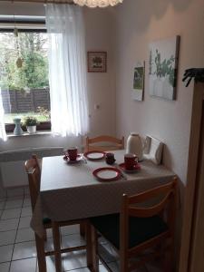 a dining room table with a table and chairs and a window at Ferienwohnung 'unter Der Linde' in Neuenkirchen +9 photos