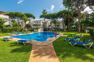 a swimming pool with blue lounge chairs in a yard at Penthouse Jacaranda in Estepona
