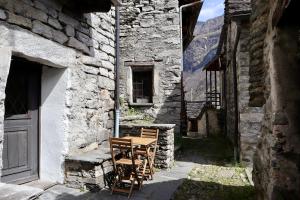 a table and chairs sitting outside of a stone building at Casa Elena Rustico storico a Corippo in Corippo