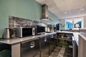 a kitchen with stainless steel appliances and a stone wall at Klönstuv in Breklum