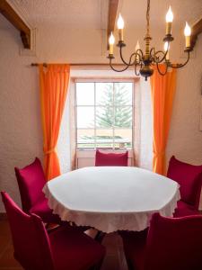 a dining room with a white table and red chairs at Villa Lomba Bela Vista in Lomba