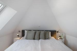 a white bedroom with a large bed with two lamps at Haus Seeblick in Göhren-Lebbin