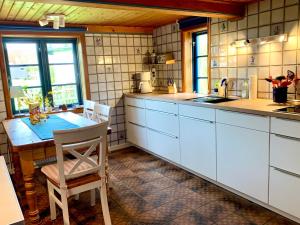 a kitchen with white cabinets and a table with chairs at Reetdachkate Müllerhaus von 1860 in Thalingburen