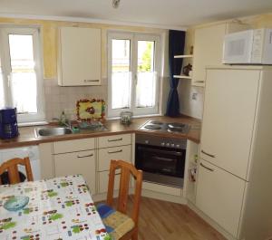 a kitchen with white cabinets and a table with a tableablish at Ferienwohnungen Sonnenblumenhaus in Bamberg +13 photos
