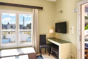 a hotel room with a desk and a television at Anemi Leros Apartments 1 in Panteli