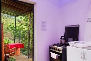 a kitchen with a stove and a window with a table at Luci's House B in São Jorge