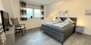 a bedroom with a bed and a chair and a television at Wiesenblick in Brilon