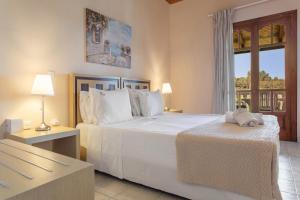 a bedroom with a large white bed and a window at Dimaras Apartments Zakynthos in Vasilikos