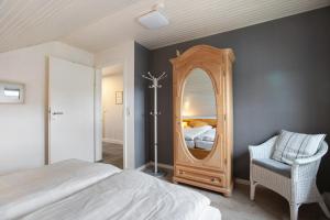 a bedroom with a mirror and a bed and a chair at Ferienwohnung Helga Bauch in Klanxbüll