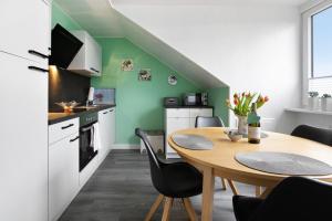 a kitchen with a table and a kitchen with green walls at Ferienwohnung Helga Bauch in Klanxbüll