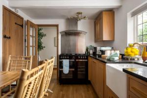 a kitchen with a stove and a table with chairs at Broadway Scandi Chic Authentic Cottage in Broadway