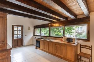 a large kitchen with wooden cabinets and windows at Les Sources Gîte La Grange in Chambonas
