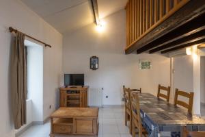 a dining room with a table and a television at Les Sources Gîte La Grange in Chambonas