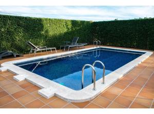 a swimming pool with two chairs and a table at Cal Torrentí in Caserras