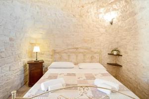 a bedroom with a bed and a stone wall at Trullo Pesco in Martina Franca