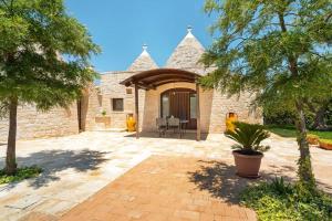 a stone house with a patio and trees at Trullo Pesco in Martina Franca