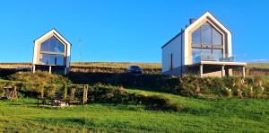 two houses on top of a grassy hill at Dom Skomackie Wzgórze widok na jezioro in Skomack Wielki