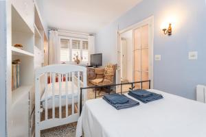 a white bedroom with a bed and a chair at Ca L' Anton in Palafrugell