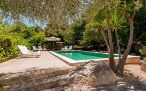 a swimming pool with two chairs and an umbrella at Es Romagueral in Artá