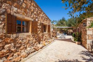 a stone house with a stone wall and a patio at Casa s’Hort - Can Rita in Llombarts