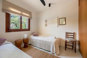 a bedroom with two beds and a window and a chair at Casa Juliarina in Sant Josep de sa Talaia