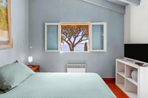 a bedroom with a bed and a window with a tree at Chambres d'hôtes - La Moustelle in La Croix-Valmer