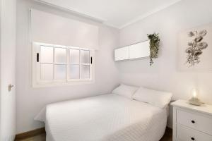 a white bedroom with a bed and two windows at Las Teresitas Beach Apartment in San Andrés