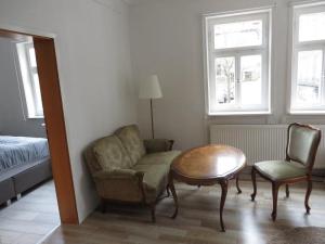 a living room with a chair and a table and a bed at Historischer Marktplatz in Spangenberg +2 photos
