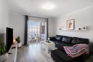 a living room with a black leather couch at Las Teresitas Beach Apartment in San Andrés
