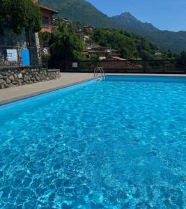 a large blue swimming pool with mountains in the background at Begna Kiddie Paradise Poolside Retreat in Porlezza
