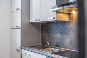 a kitchen with a sink and white cabinets at Apart Bergtraum Ried - Typ 2 in Ried im Oberinntal +16 photos