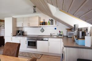 a kitchen with white cabinets and a sink at Ferienwohnung Watt'nblick in Langeneß