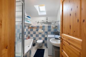 a bathroom with a sink and a tub and a toilet at Ferienwohnung Watt'nblick in Langeneß +27 photos