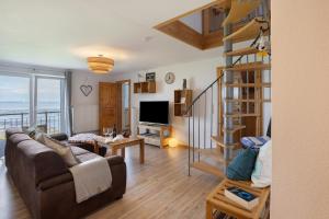 a living room with a couch and a spiral staircase at Ferienwohnung Watt'nblick in Langeneß