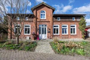 a brick house with white windows and a driveway at Fluss aufwärts in Schülp