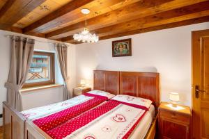 a bedroom with a bed with red and white sheets at Appartamento Zopel in Falcade
