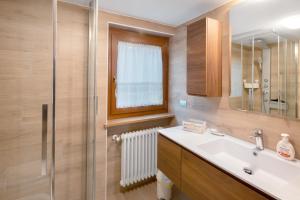 a bathroom with a sink and a mirror and a shower at Appartamento Zopel in Falcade +17 photos