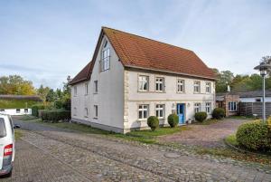 a white house with a brown roof on a street at Bäckerhus - Ferienwohnung 2 in Wiek auf Rügen